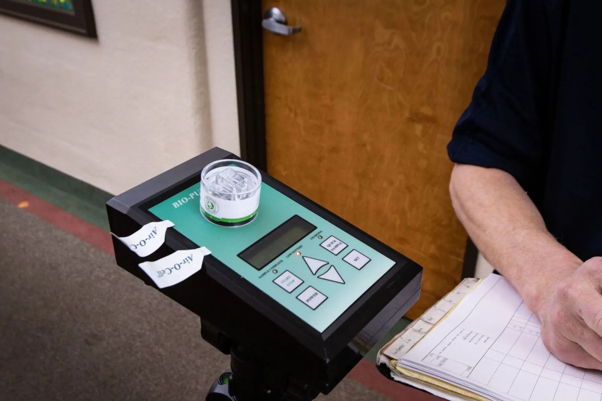 Air sampling pump with an Air-O-Cell cassette, next to the inspector's chain-of-custody log